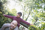 Portrait playful father carrying son on shoulders in backyard