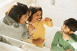 Mother and children brushing teeth in bathroom