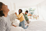 Playful mother and children enjoying pillow fight on bed