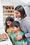 Mother and children baking muffins in kitchen