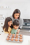 Mother and children baking chocolate muffins in kitchen