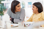 Happy mother and daughter eating breakfast