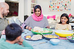 Mother in hijab enjoying dinner with family at table