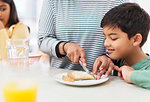 Mother cutting crusts off bread for son