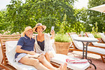 Happy mature couple taking selfie with camera phone at sunny resort poolside