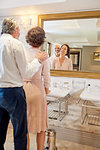 Happy mature couple standing at hotel bathroom mirror