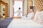 Mature couple in bathrobes relaxing in hotel bedroom