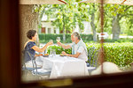 Mature couple toasting wine glasses at resort patio table