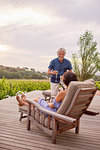 Mature couple relaxing, toasting champagne flutes on resort patio