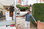 Portrait confident man carrying rug outside moving van, moving house