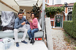 Portrait happy couple drinking tea, taking a break from moving at back of moving van