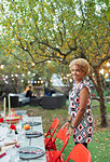 Portrait happy woman hosting dinner garden party