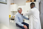 Male doctor examining senior patient in clinic examination room