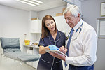 Doctor and nurse with digital tablet talking in clinic examination room