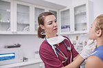 Female pediatrician examining girl in clinic examination room