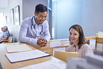 Smiling doctor and receptionist discussing medical record in clinic
