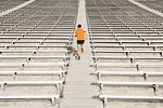 Young male runner running up stadium stairway, rear view