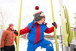 Boy with father climbing up playground slide in snow