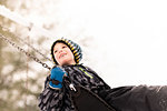 Boy in knit hat swinging on playground swing in winter