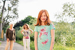 Red haired girl on rural road with mother and grandmother in background, portrait