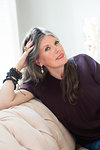 Stylish mature woman with long grey hair sitting on sofa, portrait