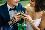 Bride and groom raising a glass in forest, cropped