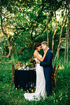 Bride and groom face to face by forest reception table