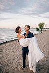 Romantic groom carrying bride on lakeside, Lake Ontario, Toronto, Canada