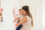 Mother hugging baby girl in room