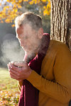 Man having warm drink against tree in park