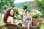 Women on wicker chairs in countryside garden, Città della Pieve, Umbria, Italy