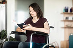 Woman in wheelchair reading at home