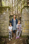Woman and two daughters standing in derelict doorway in forest, Sandpoint, Idaho, USA
