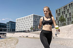 Young woman running and using smartphone in city, Berlin, Germany