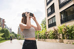 Woman using virtual reality goggles in urban Berlin, Germany