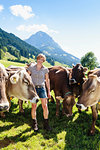 Woman bonding with herd of cows on field, Sonthofen, Bayern, Germany