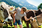 Woman bonding with herd of cows on field, Sonthofen, Bayern, Germany