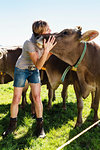 Woman bonding with herd of cows on field