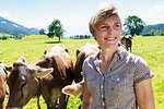 Woman bonding with herd of cows on field, Sonthofen, Bayern, Germany