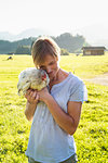 Woman carrying rooster in countryside, Sonthofen, Bayern, Germany