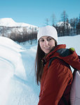 Young woman in knit hat looking back in snow covered landscape, Alpe Ciamporino, Piemonte, Italy