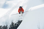 Male skier skiing mid air down snow covered mountain, Alpe-d'Huez, Rhone-Alpes, France