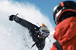 Male snowboarder speeding down mountainside, over shoulder view, Alpe-d'Huez, Rhone-Alpes, France