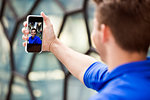 Young man taking selfie in front of glass wall, London, UK