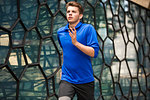 Young runner jogging past glass wall, London, UK