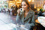 Young woman drinking coffee with friend in cafe, London, UK