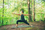 Woman doing warrior pose in forest