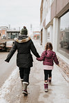 Mother and daughter walking past shop in winter