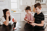 Mother and children playing cards in kitchen
