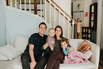 Mid adult couple on sofa with baby son and toddler daughter, portrait